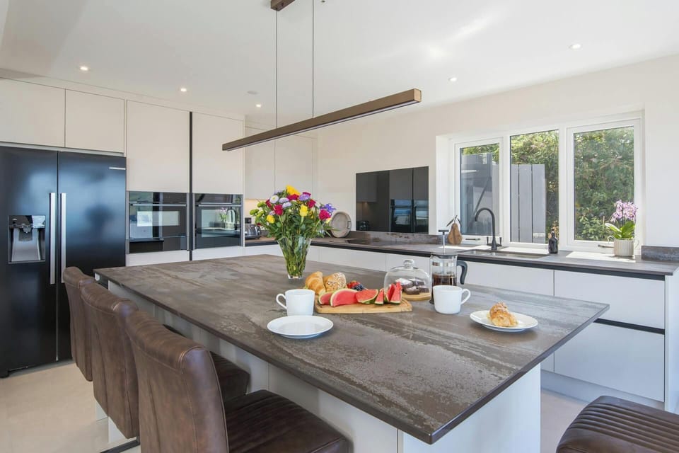 Kitchen island set with coffee cups, croissants and fruit, with vase of flowers