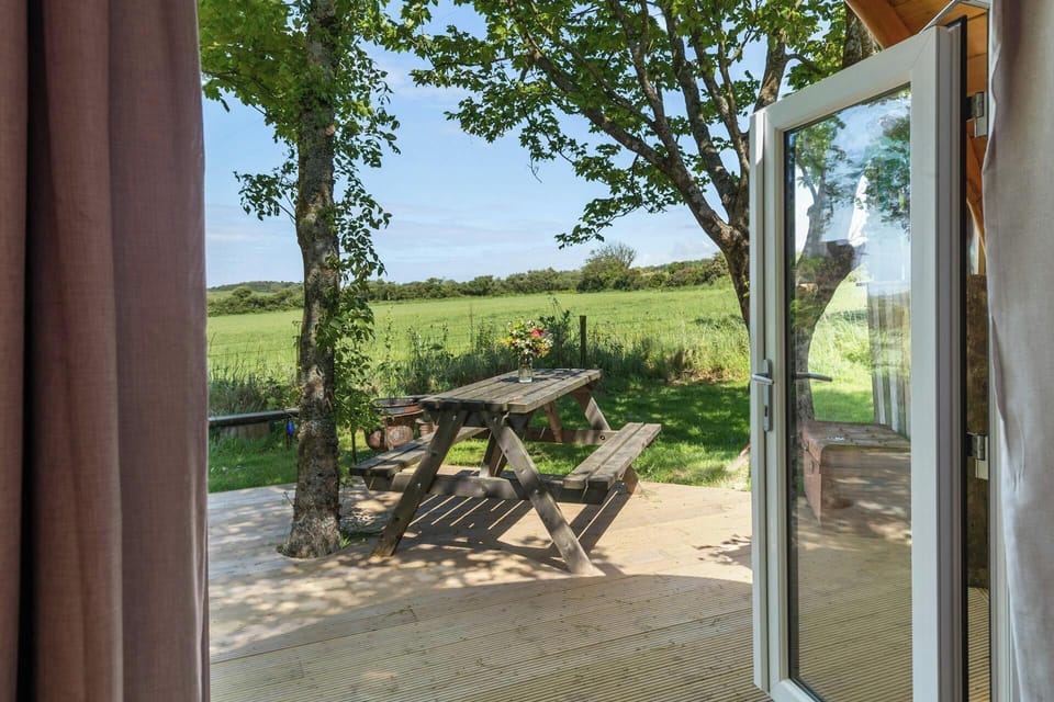 Wooden picnic table under trees on patio with countryside view