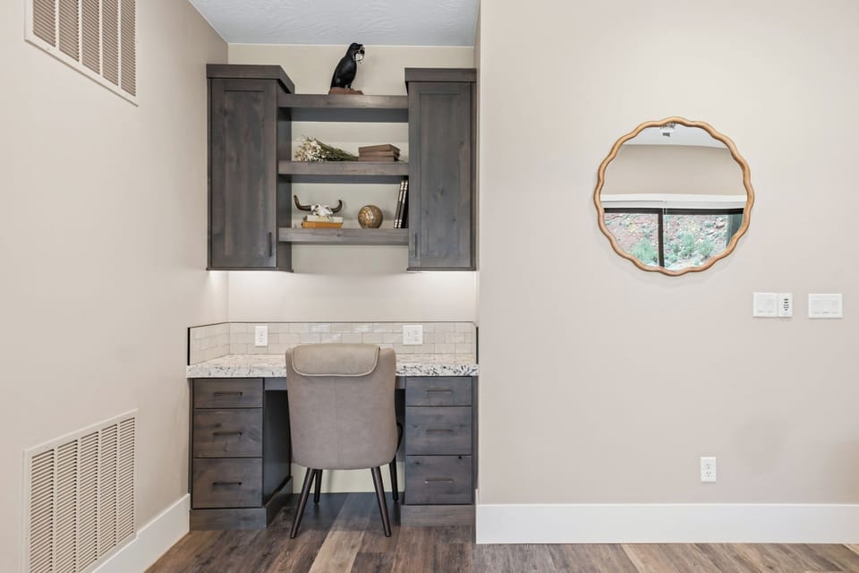 Cozy built-in workspace with granite countertop, wood shelving, and round mirror accent