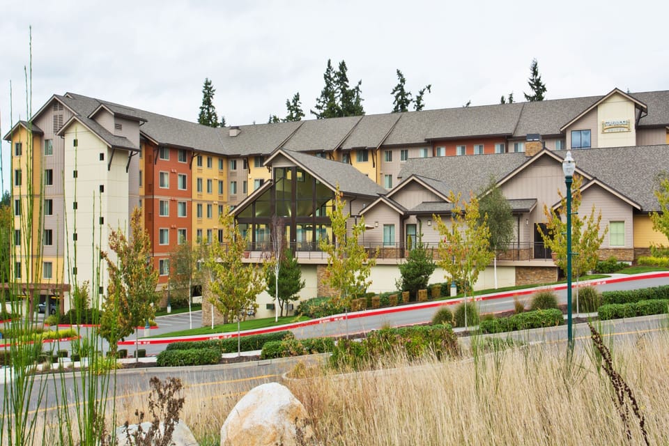 Earthy stone and wood tones define the building's exterior amid mature landscaping