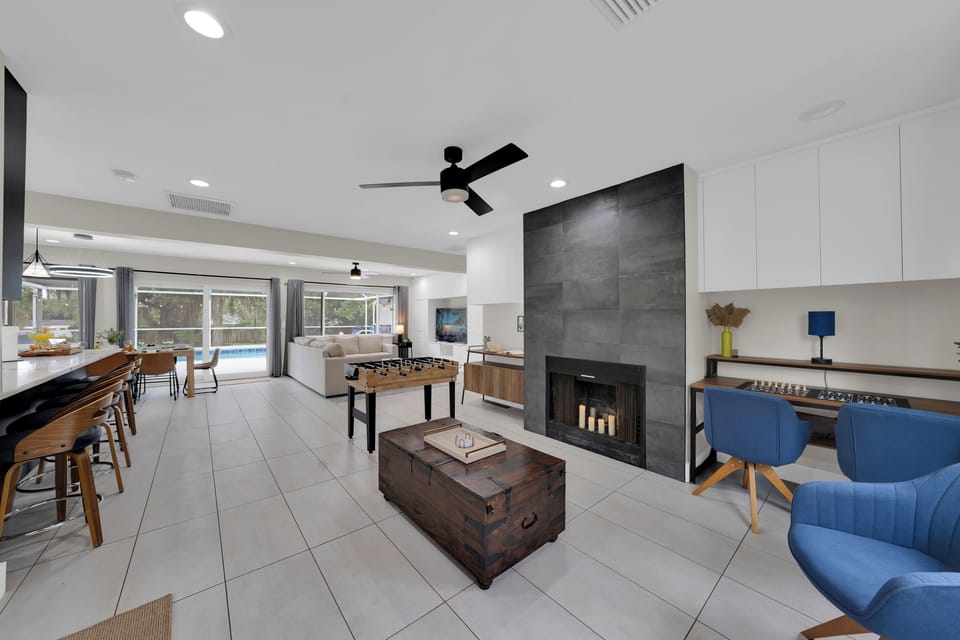The perfect first impression: a warm living space with a cozy fireplace, generous seating, and views stretching all the way to the pool.
