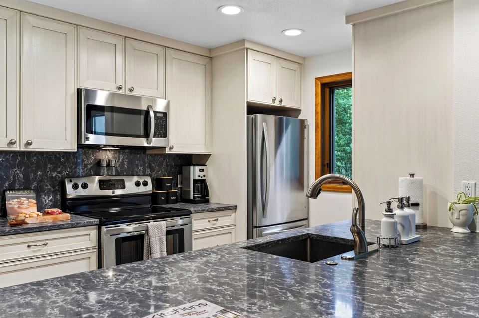 Prepare meals in the fully equipped kitchen, featuring stainless steel appliances and generous counter space.
