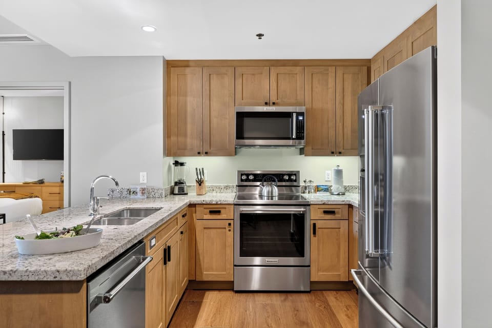 A fully equipped kitchen features granite counters, stainless steel appliances, and breakfast bar seating for casual meals.