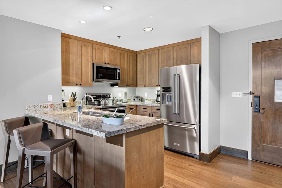 A fully equipped kitchen features granite counters, stainless steel appliances, and breakfast bar seating for casual meals.