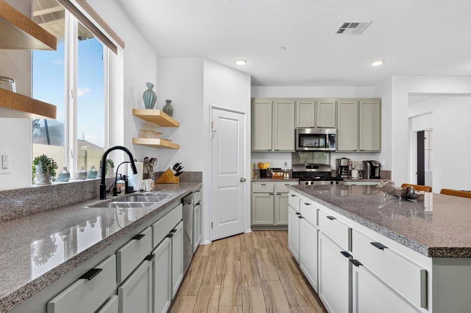 Bright kitchen with stainless steel appliances, white cabinetry, and granite countertops.