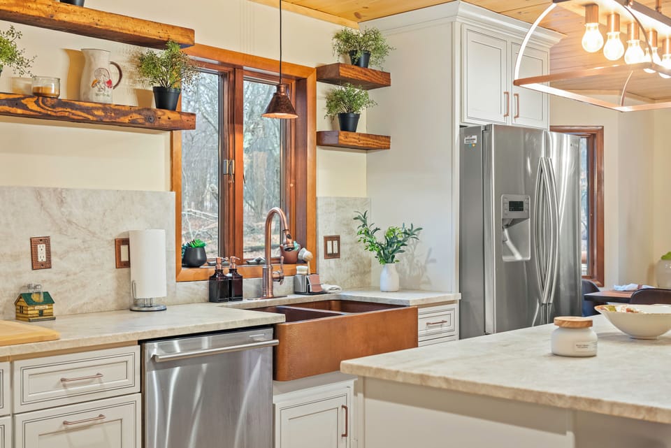 A bright kitchen pairs stainless steel appliances, a generous island, and warm wood ceilings for an inviting place to cook and gather.