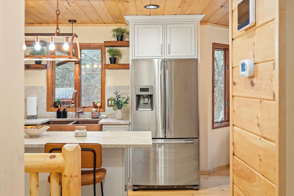 A bright kitchen pairs stainless steel appliances, a generous island, and warm wood ceilings for an inviting place to cook and gather.