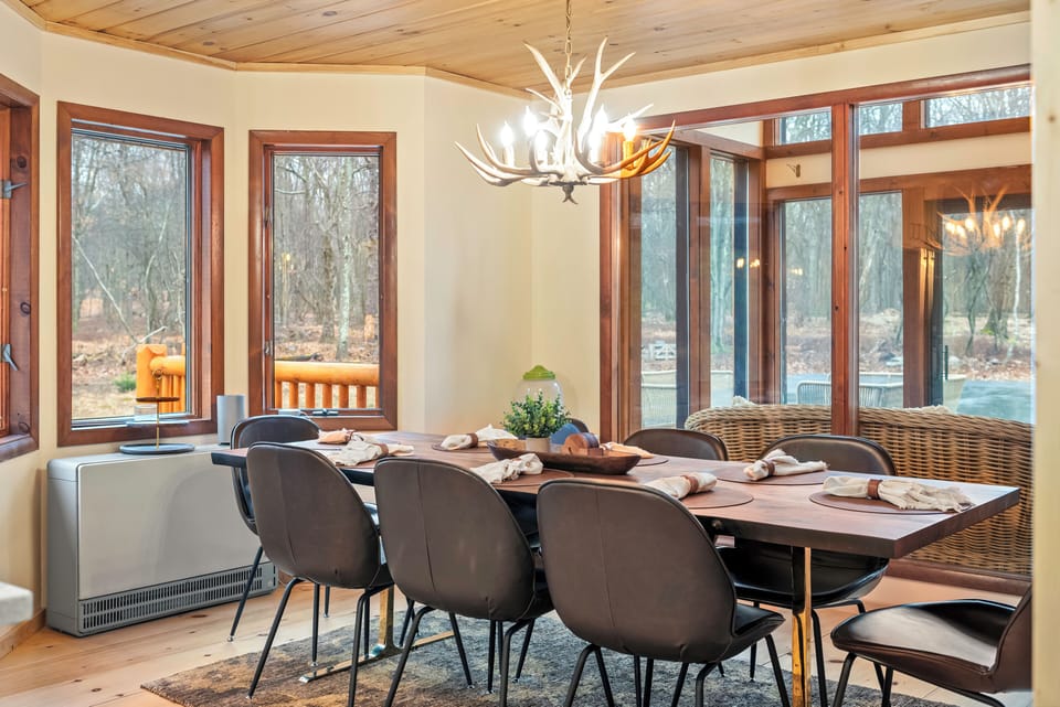 Relax on the expansive deck with multiple lounge areas and peaceful woodland views stretching beyond the patio.