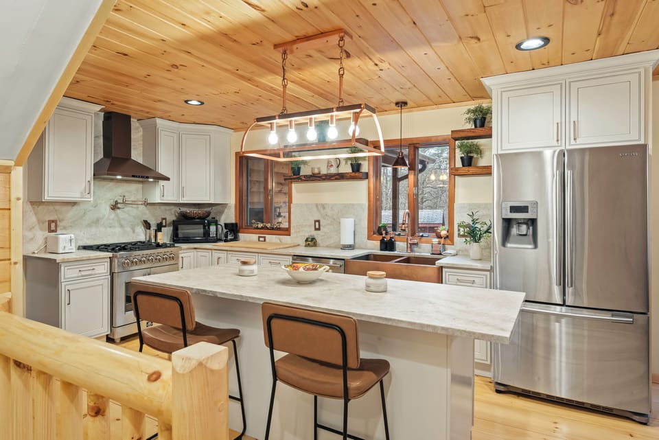A bright kitchen pairs stainless steel appliances, a generous island, and warm wood ceilings for an inviting place to cook and gather.