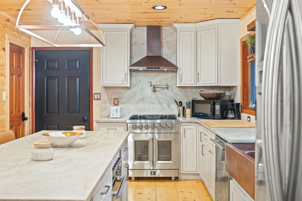 A bright kitchen pairs stainless steel appliances, a generous island, and warm wood ceilings for an inviting place to cook and gather.