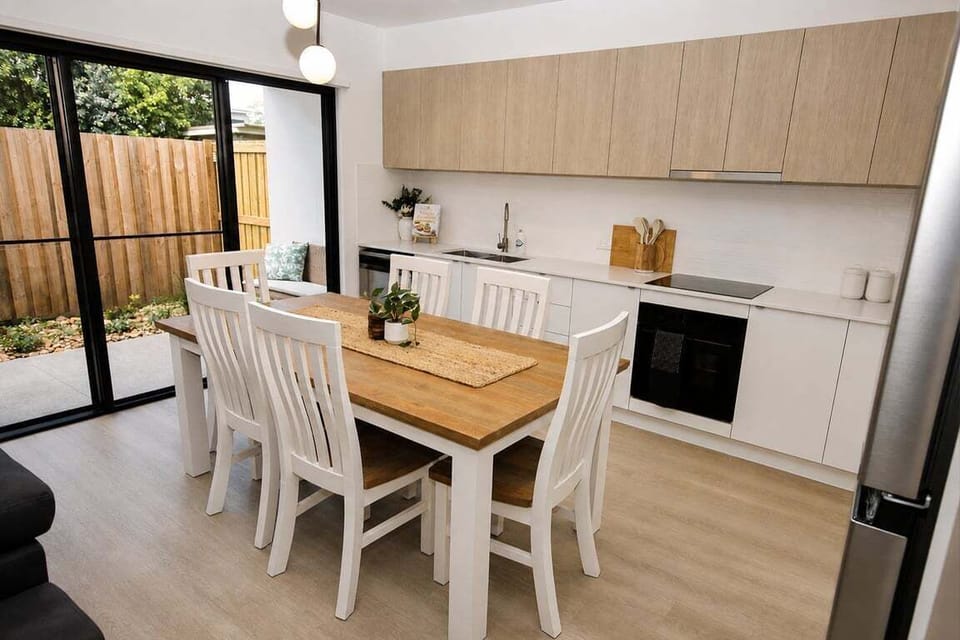 Kitchen & Dining – modern open-plan kitchen with 6-seater dining table & sliding doors creating an easy indoor-outdoor entertaining space.