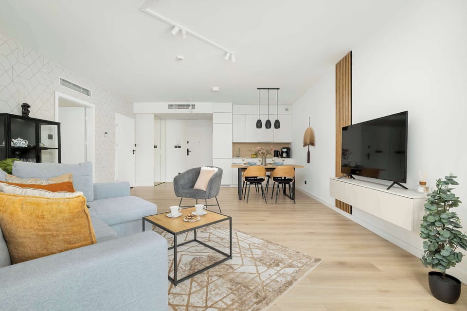 Looking from the living room corner, the view highlights the TV mounted on a wood-paneled wall section next to the dining area and sofa.