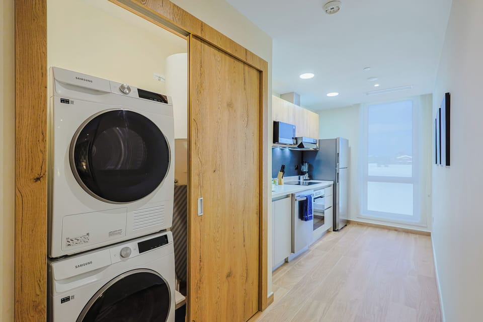 Your modern vacation space includes a stacked washer and dryer tucked neatly behind sleek sliding doors, plus a bright kitchen with everything you need for effortless meal prep and easy mornings.