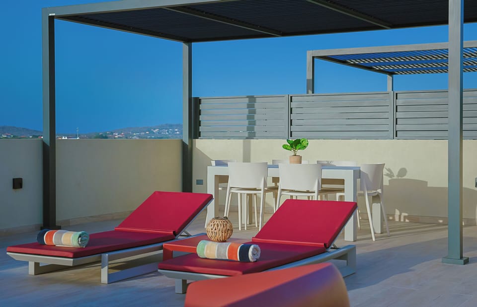 Unwind on your private terrace with comfortable loungers, a shaded pergola, and an outdoor dining area perfect for sun-soaked afternoons and warm evenings under the sky.