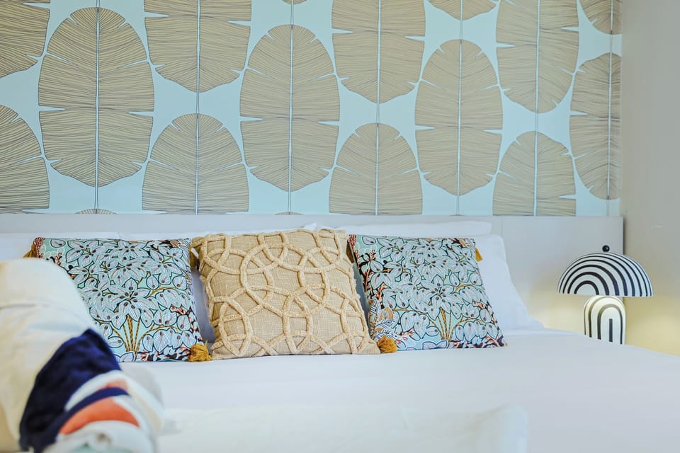 Sink into crisp white linens accented by stylish pillows and eye-catching modern wall. This bedroom invites peaceful rest, blending serene coastal tones with playful, curated details you'll love.