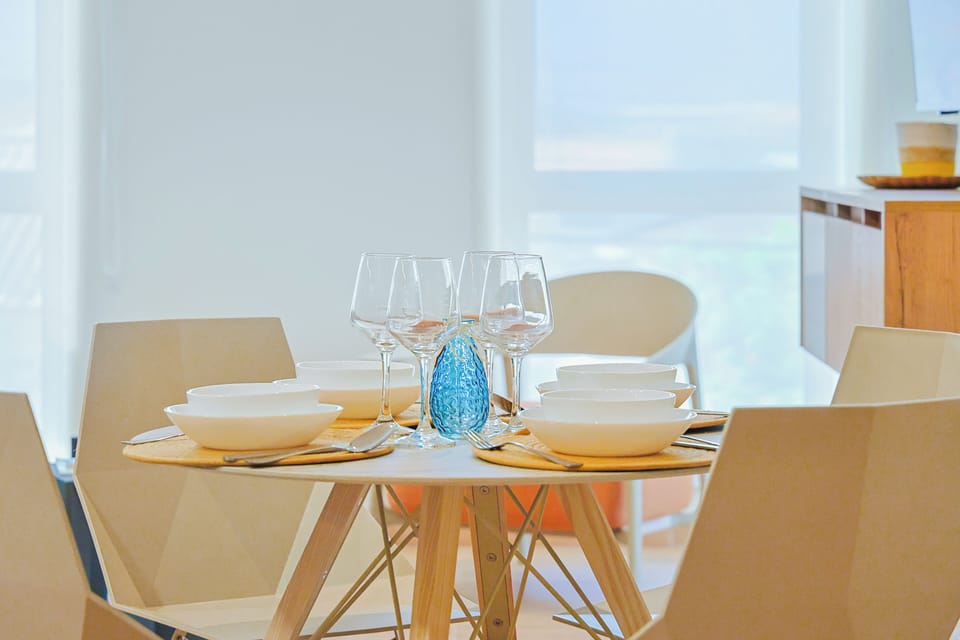 Gather around this bright and inviting dining table, thoughtfully set for shared meals and meaningful conversations. Clean lines, natural wood accents, and soft lighting create a warm and welcoming atmosphere.