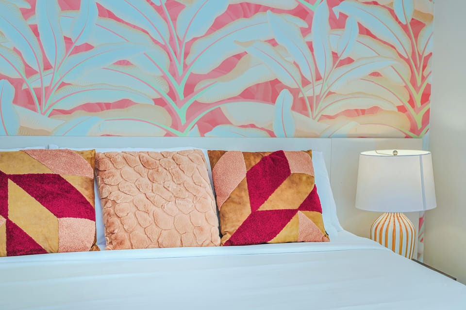 Drift off beneath a vibrant tropical leaf mural in your serene coastal getaway. Plush geometric pillows add a playful pop of warmth and color, inviting you to sink into comfort.