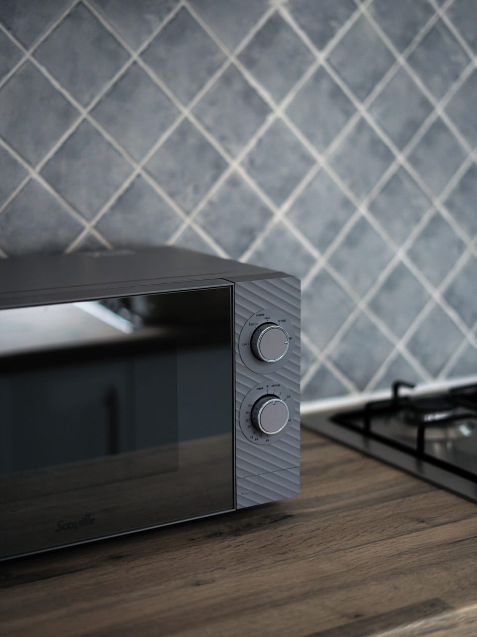 Modern kitchenette with microwave, gas cooktop, and stylish tile backsplash