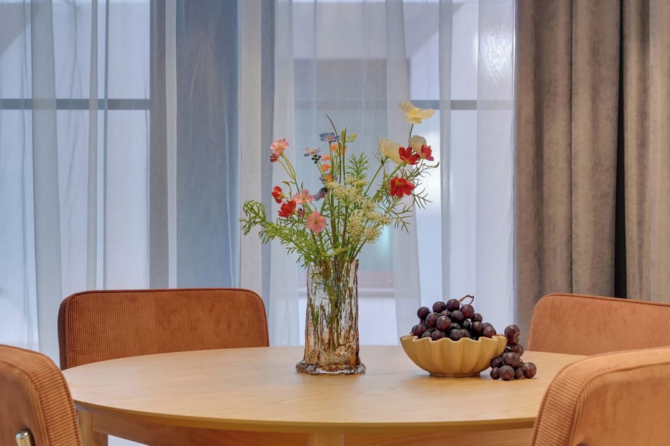 Elegancki i przytulny salon z wygodną sofą oraz stylową strefą jadalnianą. Ciepłe oświetlenie, drewniane akcenty i dekoracyjny dywan tworzą wyjątkową, harmonijną przestrzeń idealną do relaksu i wspólnego spędzania czasu.