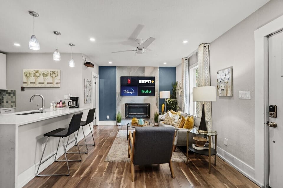 Cook, dine, and lounge in one connected space anchored by a bar-height island and Smart TV over the fireplace.