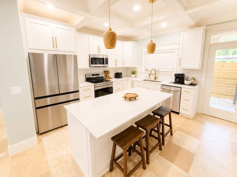 The fully-equipped chef`s kitchen features a large island, stainless appliances, and seating for casual bites.