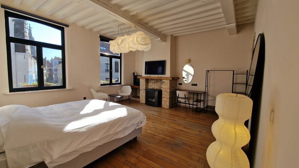 Sleep beneath a floating cloud: the Belux Cloud XL above the kingsize bed, with the original fireplace and smart TV close by.
