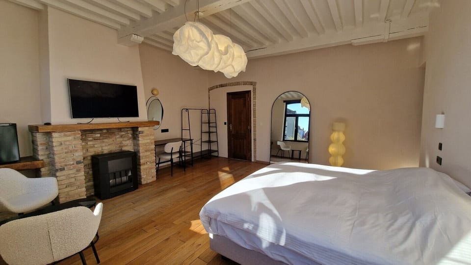 Sleep beneath a floating cloud: the Belux Cloud XL above the kingsize bed, with the original fireplace and smart TV close by.