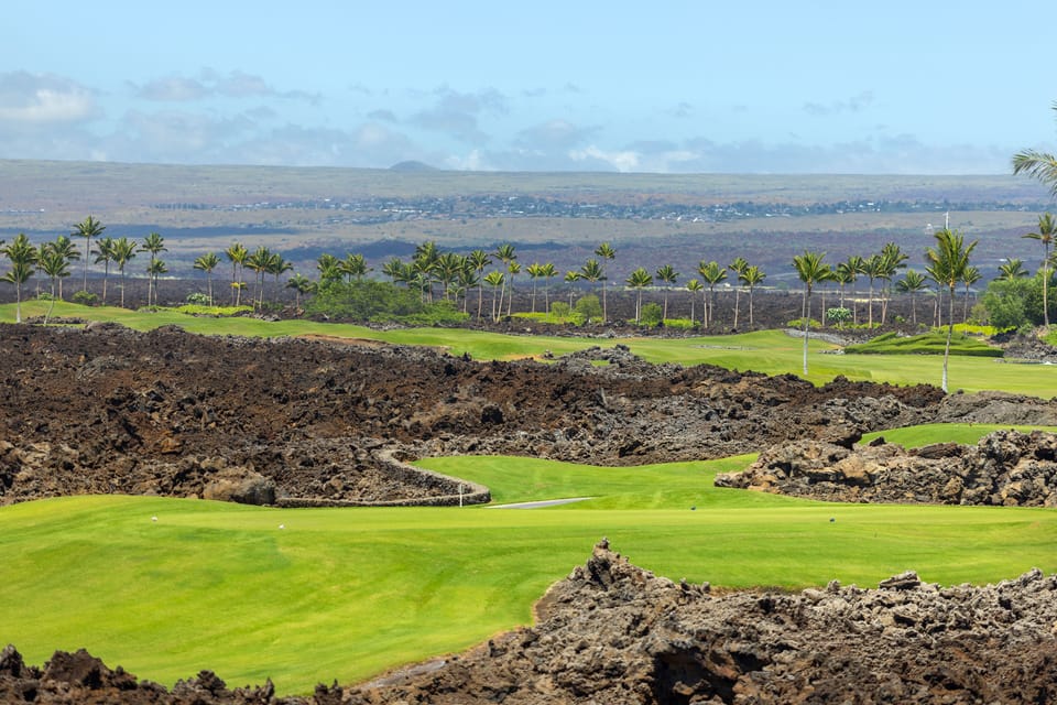 Lush fairways stretch toward the majestic mountains beyond.