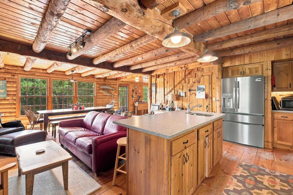 The open layout keeps the kitchen, dining, and living areas connected, with windows framing the trees on every side.
