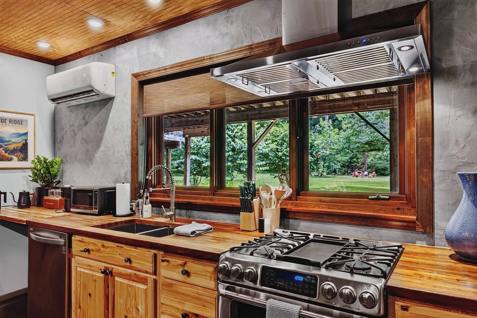 Fully equipped Garden Suite kitchen with a gas range, dishwasher, microwave, and sink overlooking the greenery.