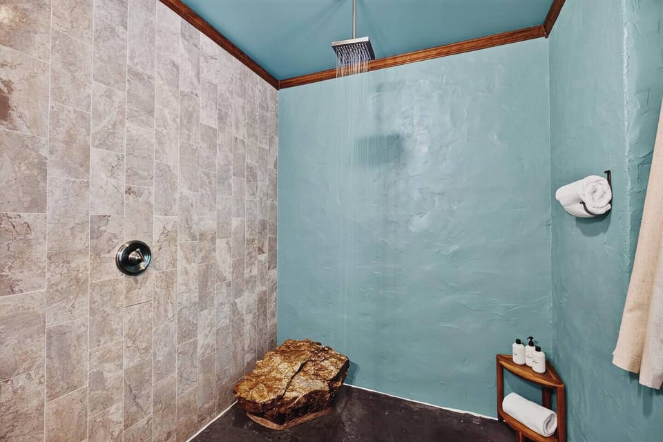 Spa-like walk-in shower with rainfall showerhead, fresh towels, and natural stone accents.