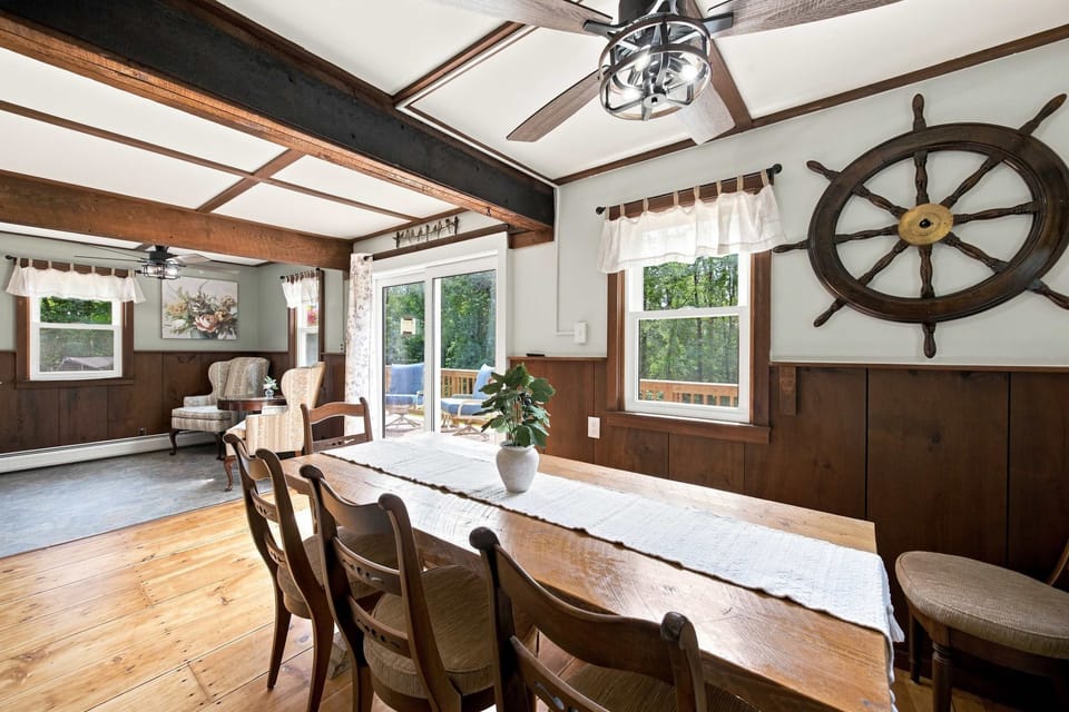 Wide wood-plank floors and windows on multiple sides bring the treeline into the dining area.