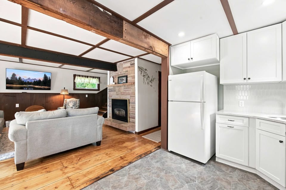The main level opens up with a sofa facing the TV and fireplace, and the kitchen just steps away.