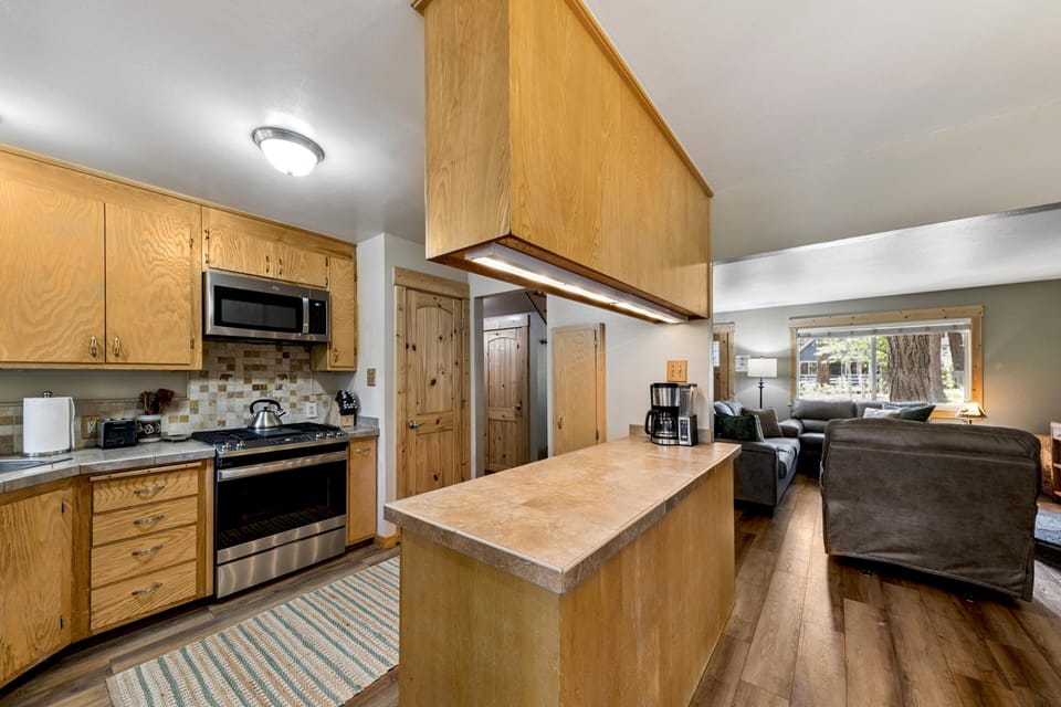 Tile countertop peninsula separates the kitchen with oak cabinets from the living area with leather couches and large window.