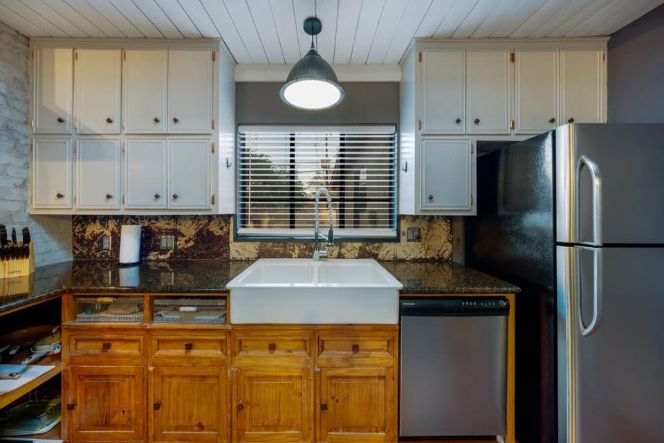 Built for Real Cooking — A deep double farmhouse sink, granite counters, dishwasher, and a vintage pressed-tin backsplash you`ll want to photograph