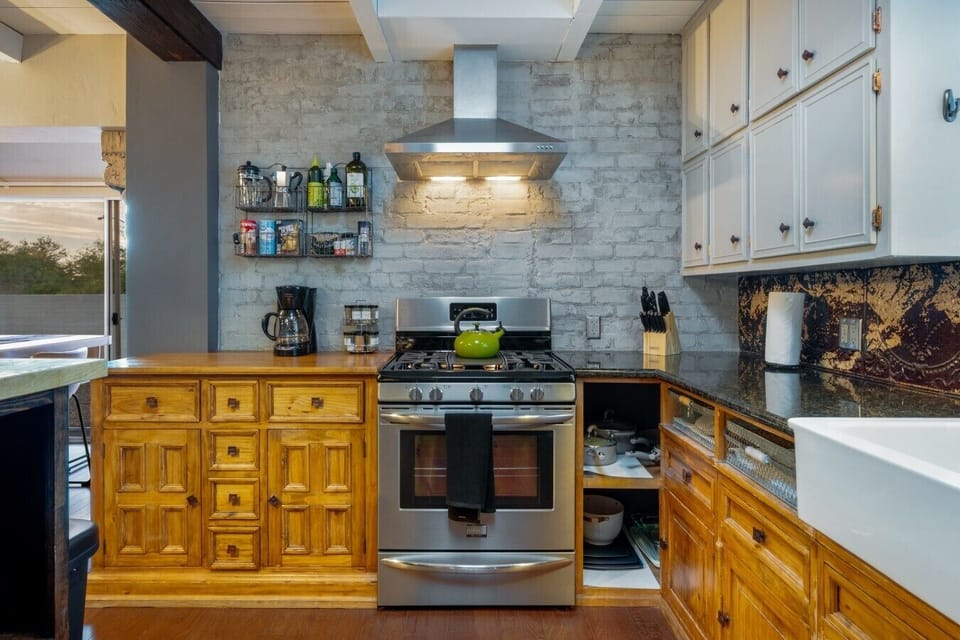 Fire Up the Gas Range — Full gas range under a vented hood, with pots, pans, knives, spices, and a coffee maker already waiting for you