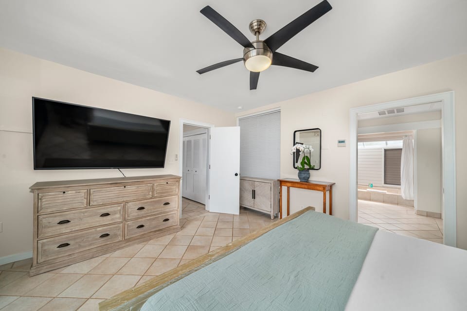 Primary suite with a king bed, large TV, and ensuite bathroom access.
