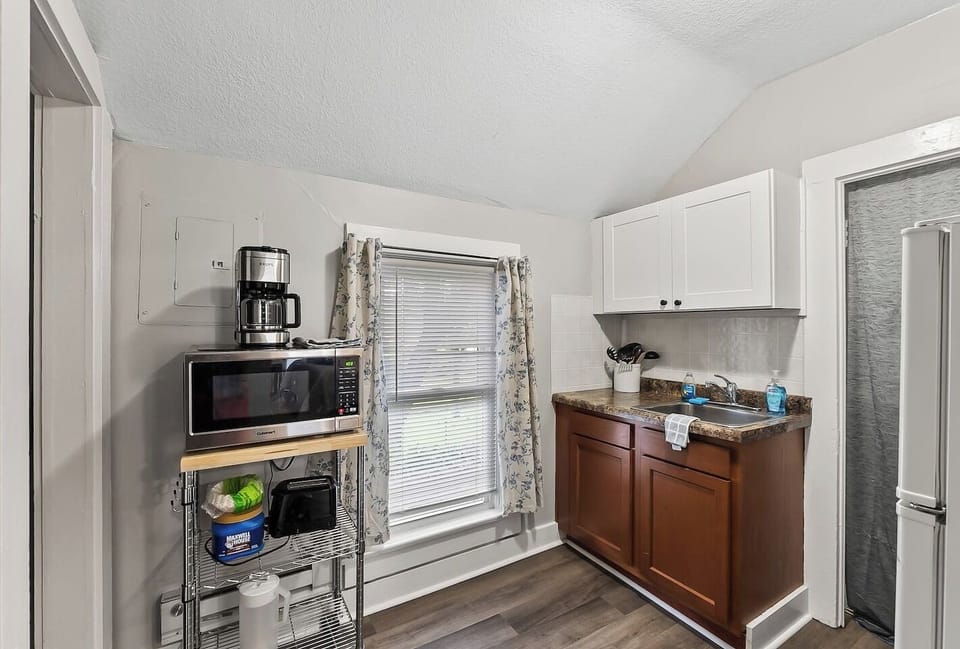 A compact kitchenette with everything you need — microwave, coffee maker, and full-size fridge tucked neatly into the space.