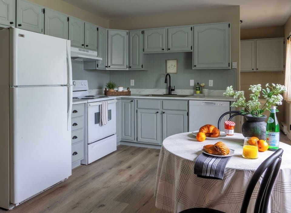 Sage cabinetry and classic finishes give the kitchen a cheerful, homey character.