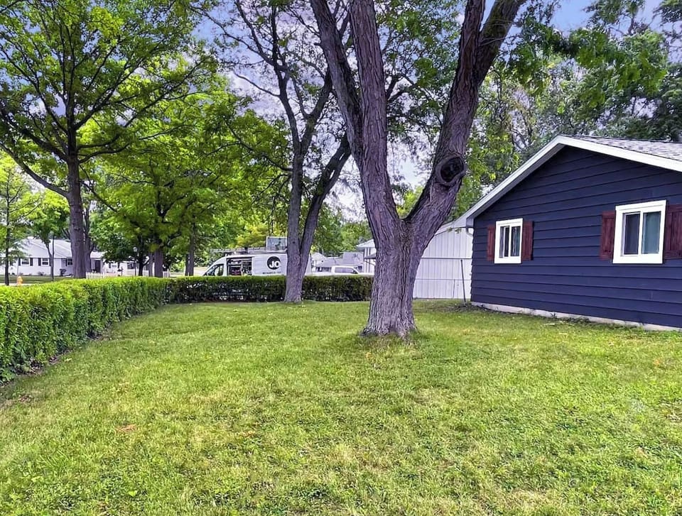 Mature shade trees and a tucked-away hedge line make this backyard feel like your own quiet retreat.