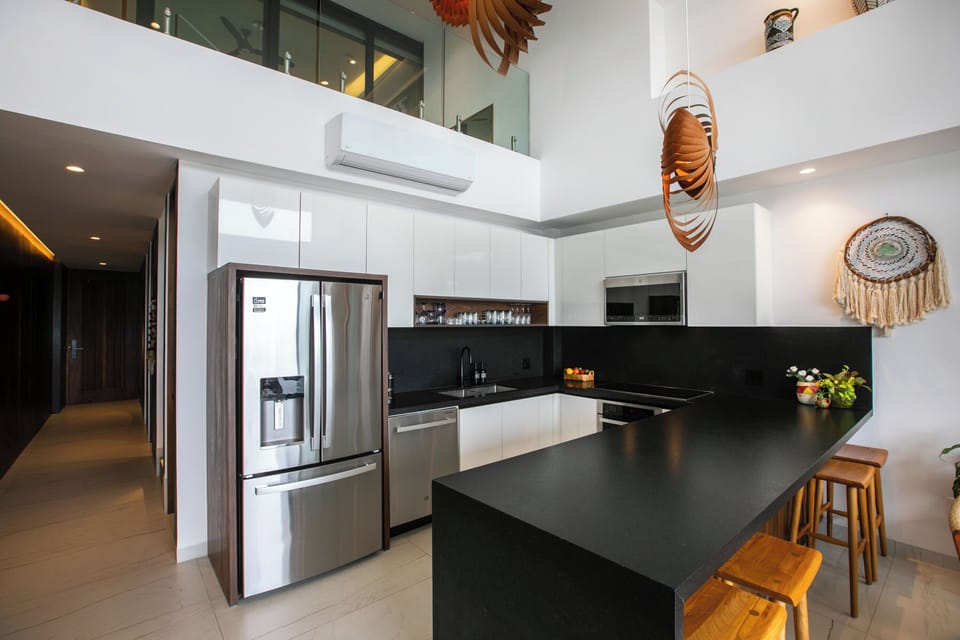 Your modern kitchen invites with sleek white cabinetry and black stone counters, accented by sculptural wood art