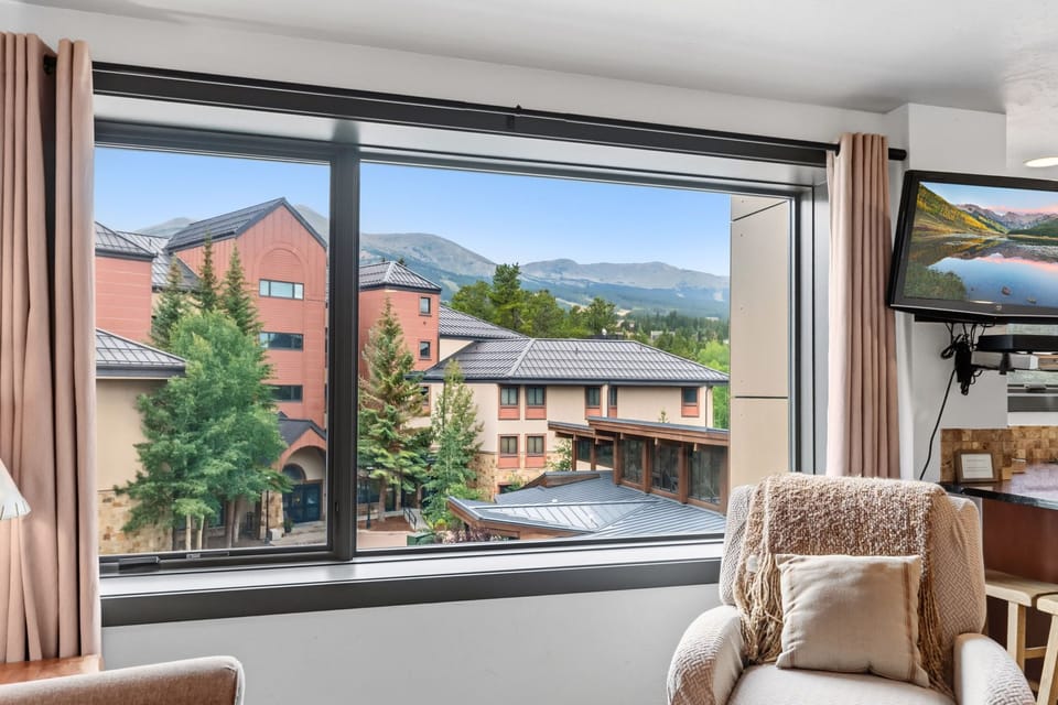 Sink into your cozy armchair and let your gaze drift across the majestic mountain skyline framed by sweeping windows—your perfect retreat for morning coffee or evening relaxation.
