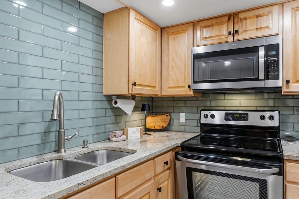 Your fully equipped kitchen features modern appliances and a calming tile backsplash, ready for preparing meals during your getaway.