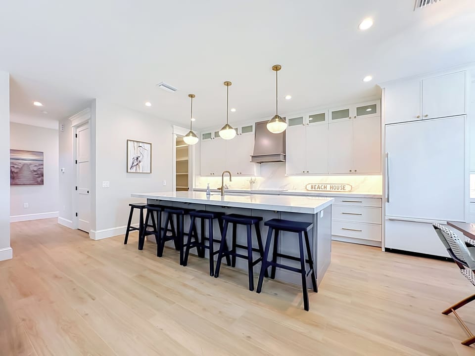 Gather around your spacious kitchen island with seating for four, where coastal charm meets modern elegance. The bright, open layout and warm wood floors create the perfect spot for morning coffee or casual meals together.