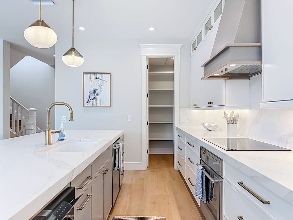 Elegant white kitchen awaits your culinary adventures, with sleek marble counters, modern appliances, and a thoughtfully designed pantry to keep everything organized and within easy reach.