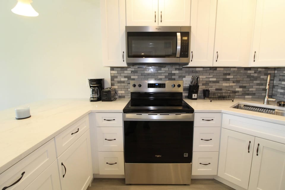 The rang/oven and microwave against the beautiful newly tiled backsplash.