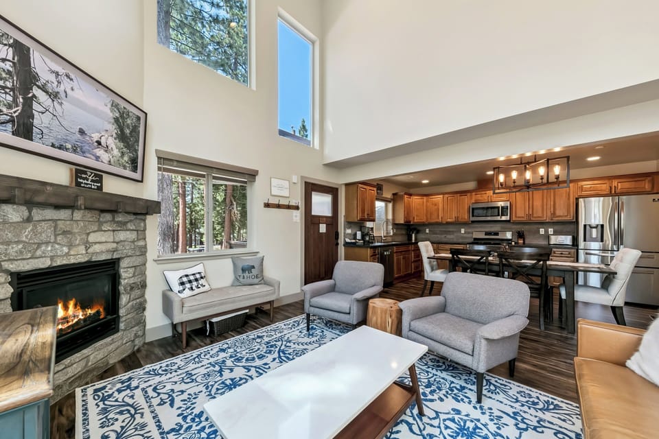 Unwind in your open-concept living space where high ceilings and natural light create an airy retreat. A crackling stone fireplace, cozy seating, and a fully equipped kitchen await—perfect for gathering after mountain adventures.