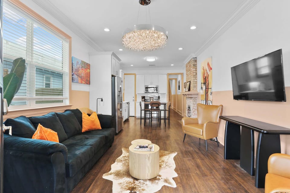 Bright open living room with comfortable seating, Smart TV, colorful artwork, hardwood floors, and an easy flow into the dining and kitchen areas.