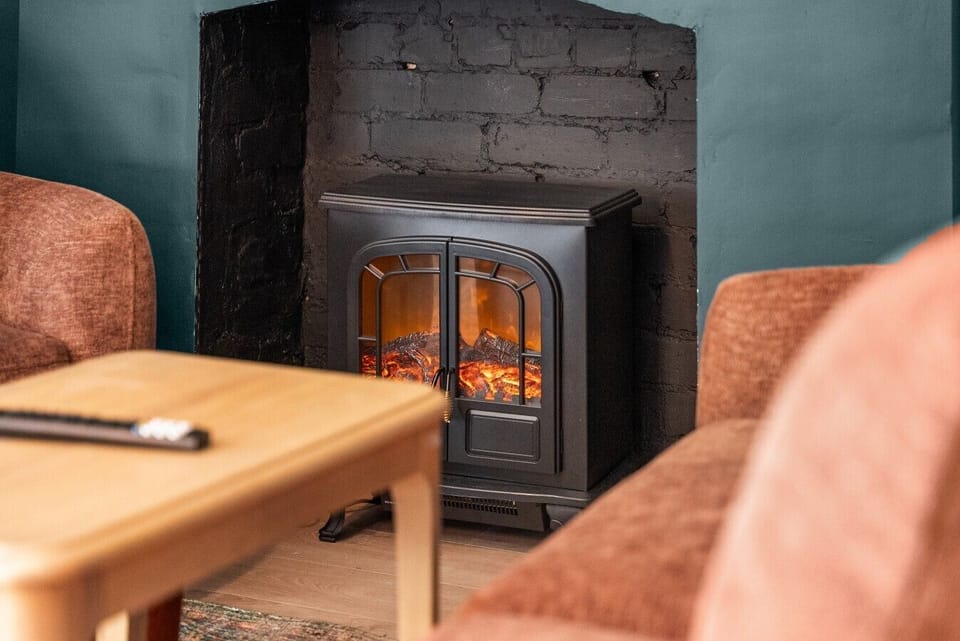 Cosy up in the ground-floor living room beside the electric stove, perfect for relaxing after a day out.