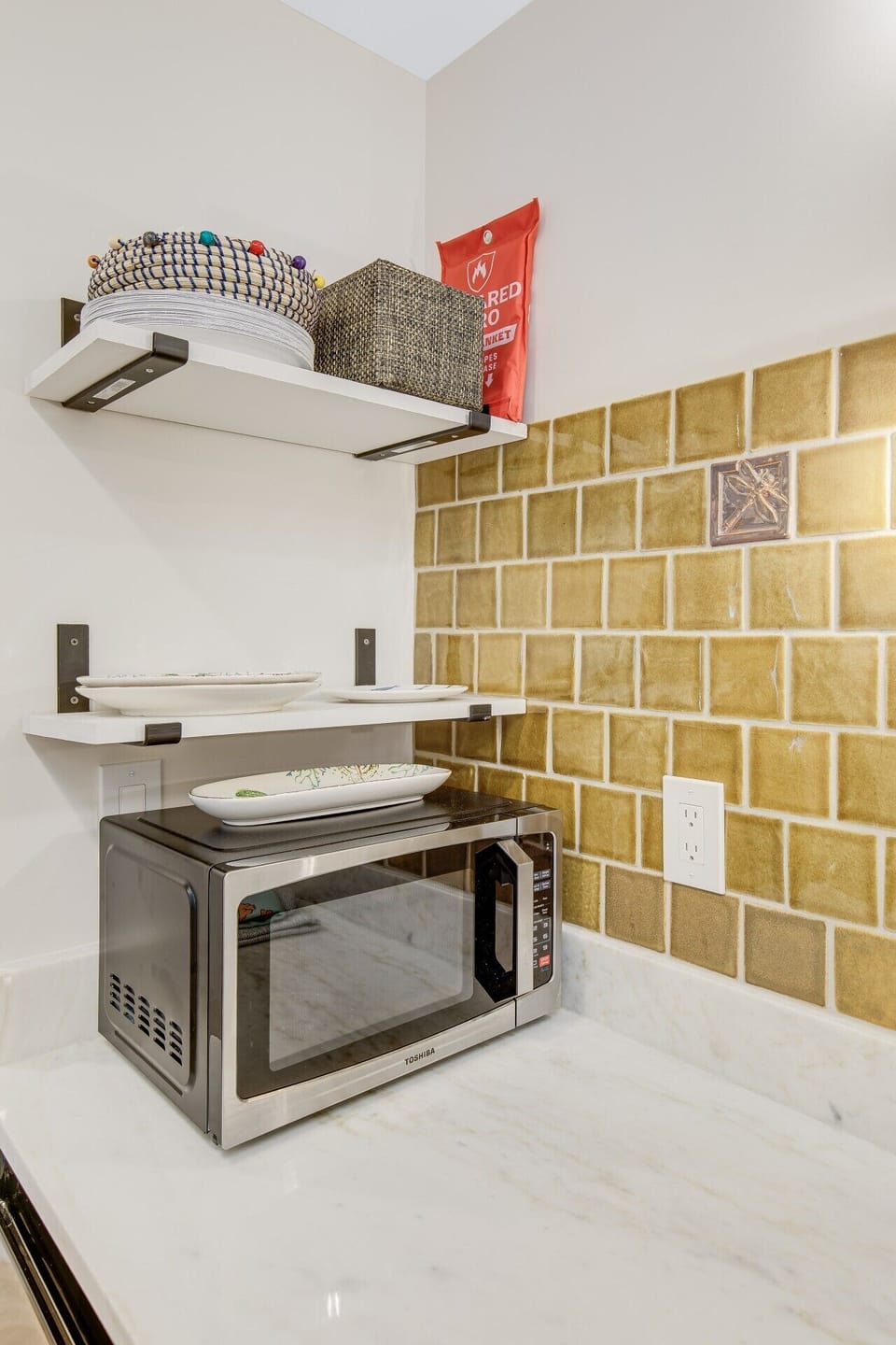 Dedicated microwave nook with wall-mounted shelving for extra storage and dishware.